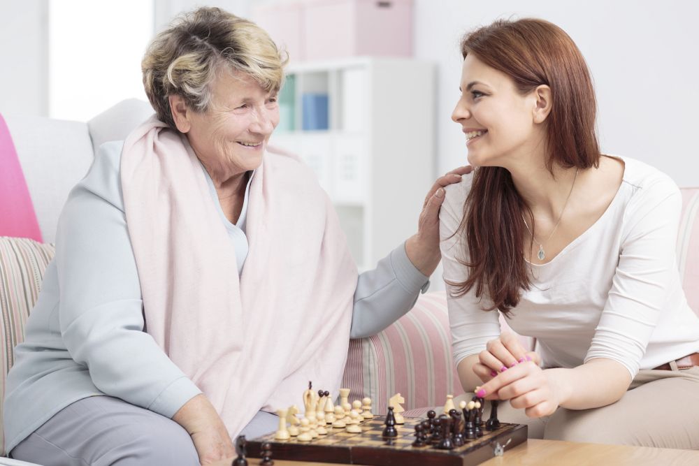 Opiekunka grająca z seniorką w szachy